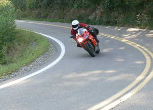 Body position helps drop the bike into the turn while requiring less lean angle.